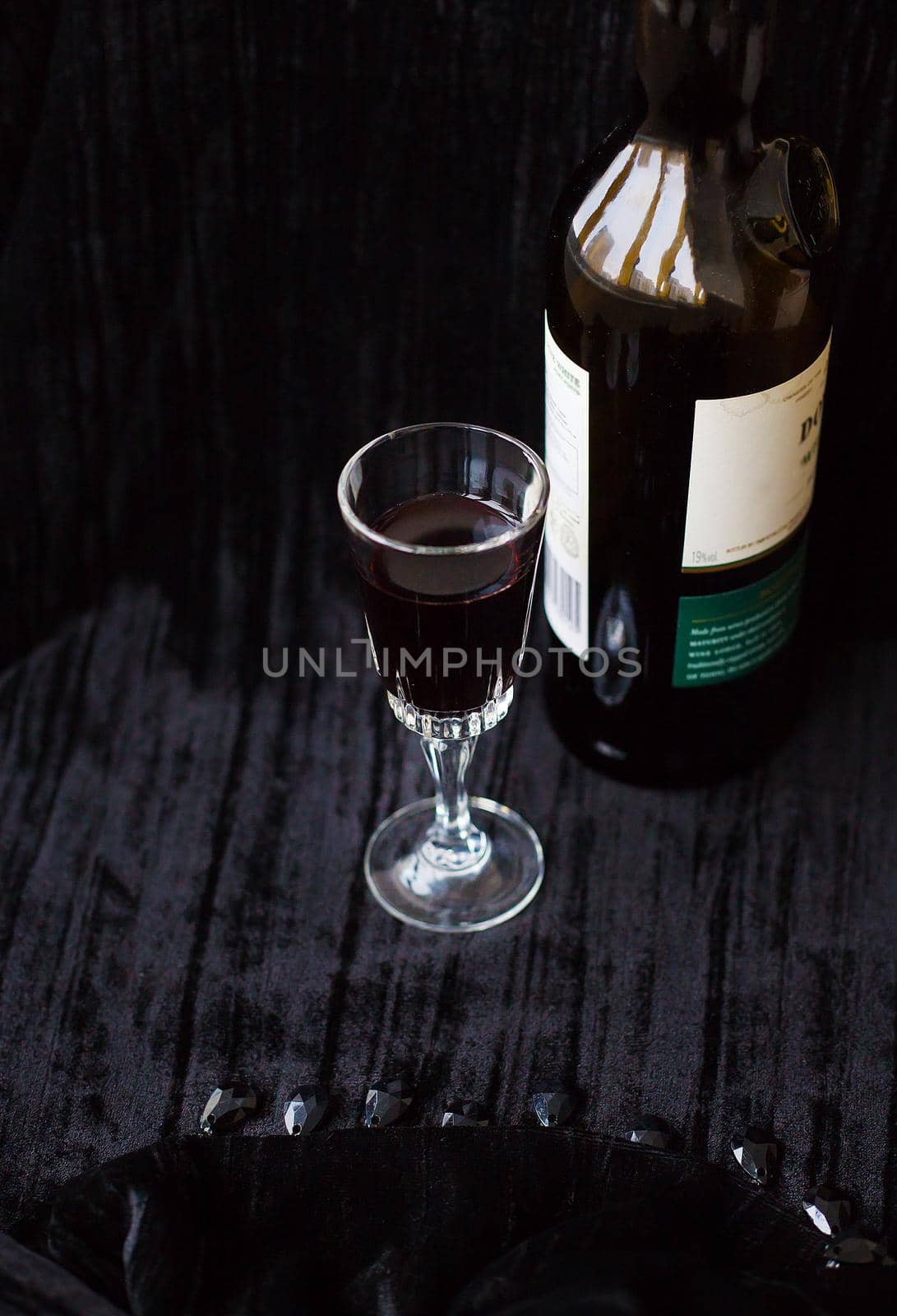bottle and a glass of red wine on a black background