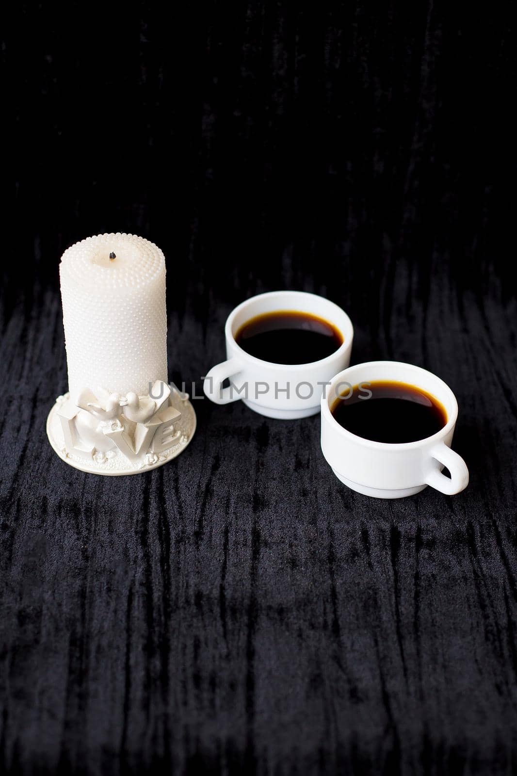 candle and two cups of coffee on a black background.