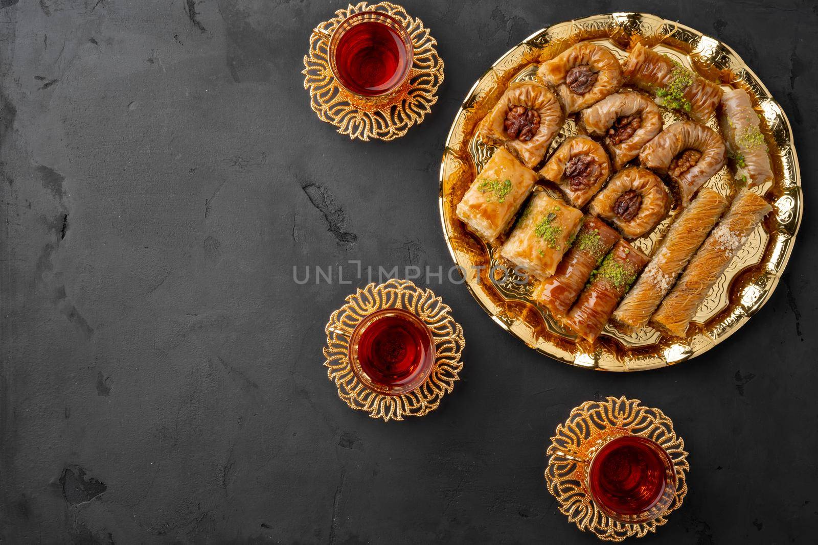 Turkish tea in traditional glasses baklava on black background, top view