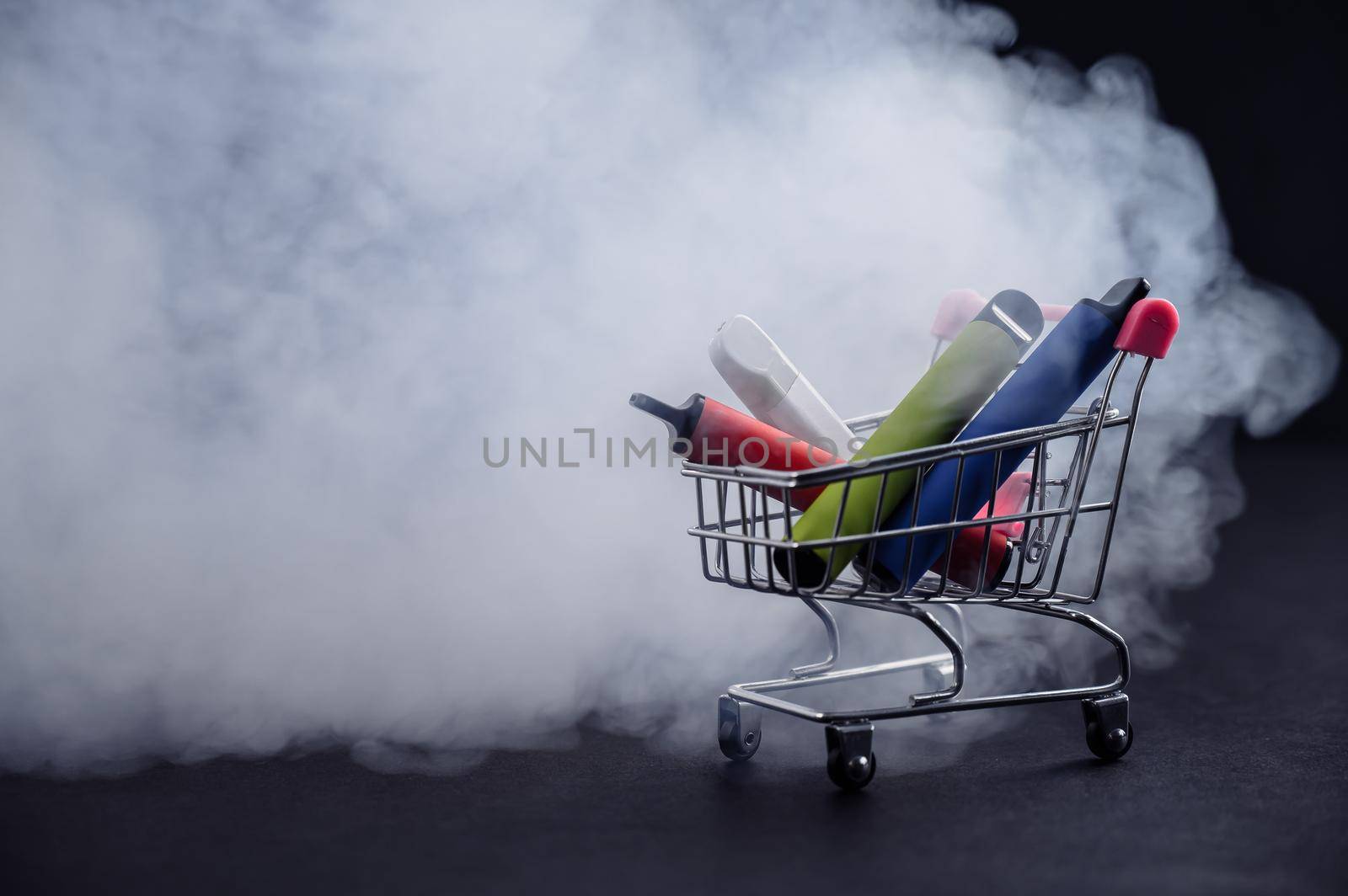 Disposable vapes in a shopping cart on a black background. Modern electronic cigarettes. by mrwed54