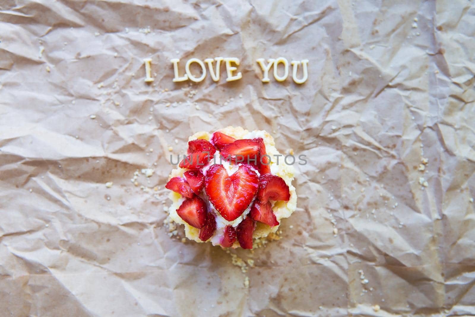 Bright cupcake with strawberries lies on craft paper, the inscription I love you by sfinks
