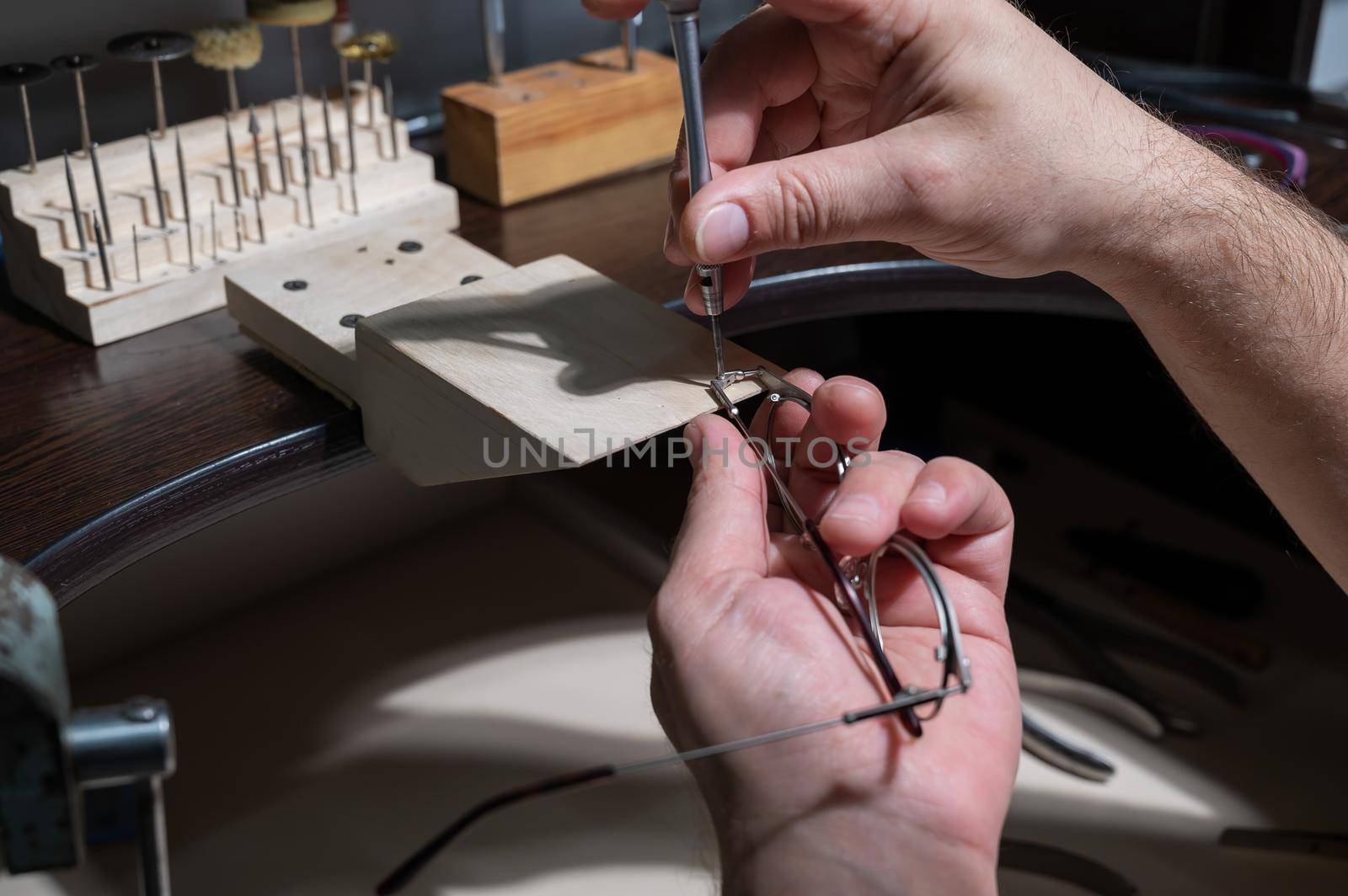 Optical technician fixing glasses. Close-up of male hands with screwdriver and goggles frame. by mrwed54