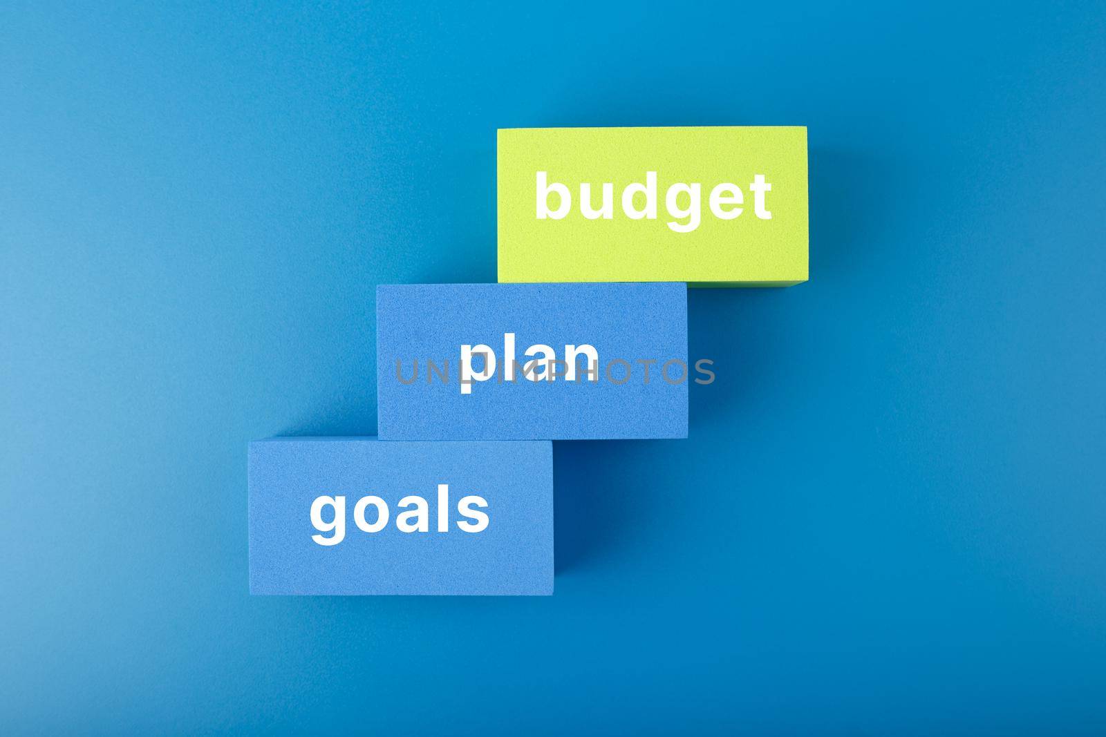 Business plan concept. Budget, plan, goals written on colored blue and yellow rectangles on dark blue background. Financial goals 