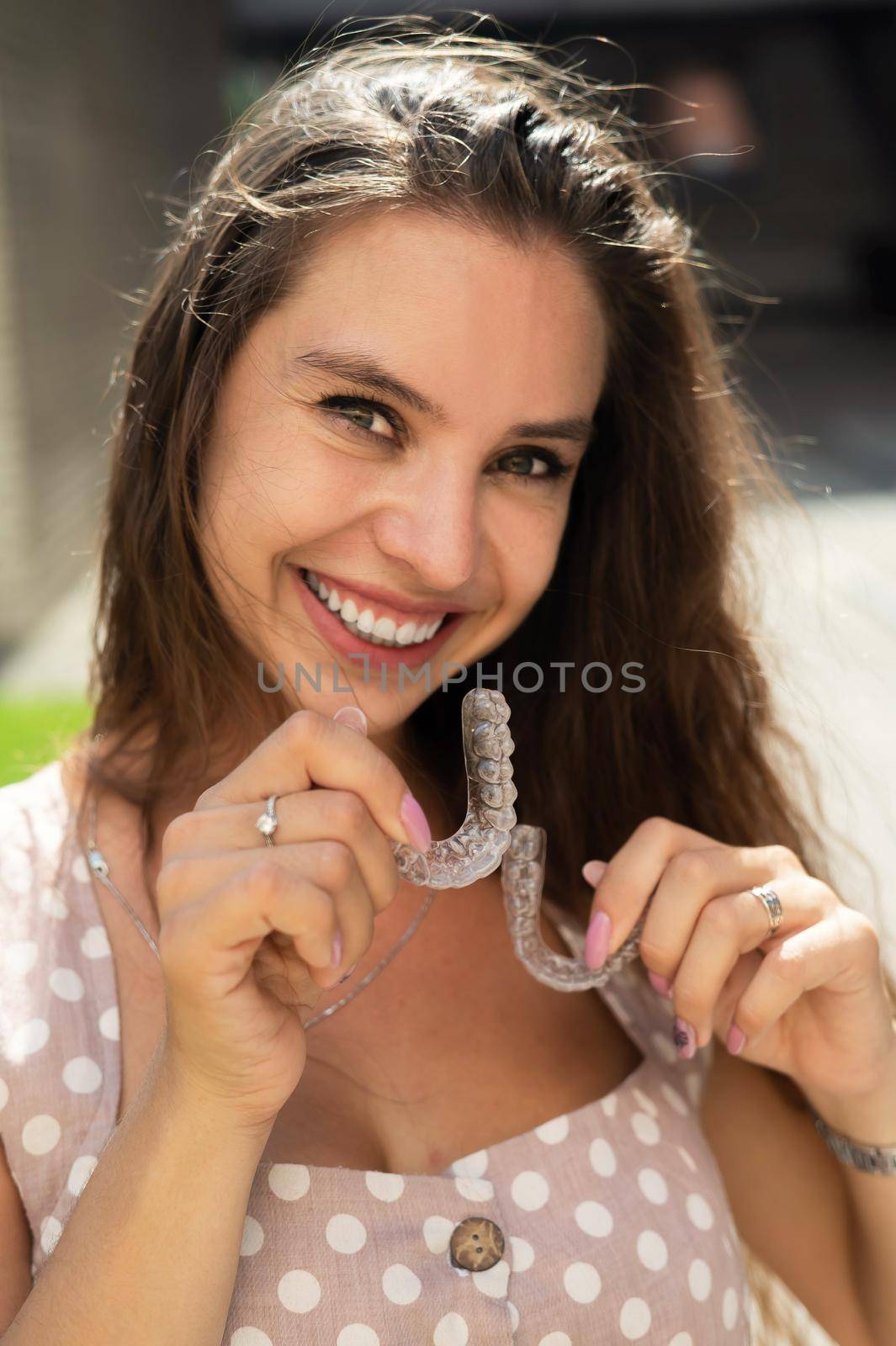 Beautiful caucasian woman holding transparent mouth guards for bite correction
