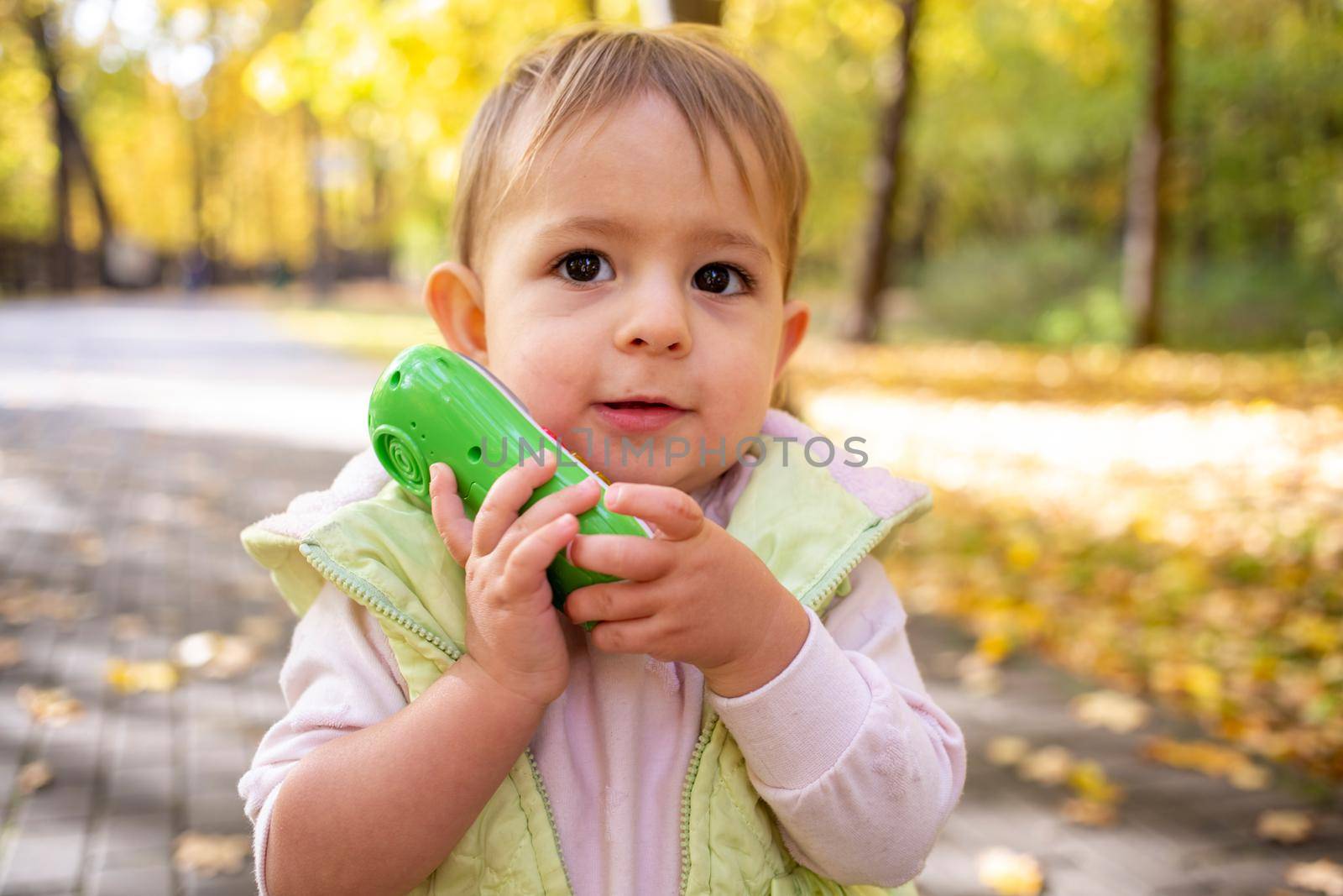 portrait of cute toddler playing talking on a toy phone.