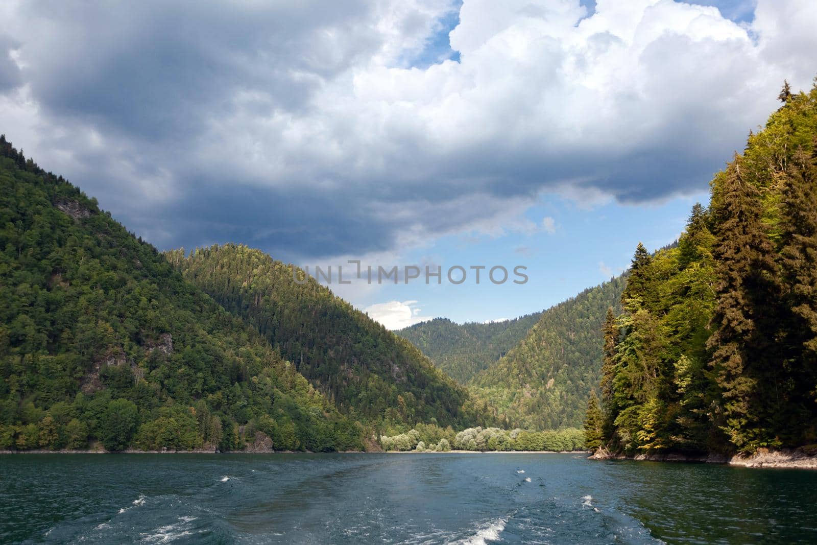 Beautiful high mountains against a blue sky with clouds in the foreground green mountain lake, used as a background or texture