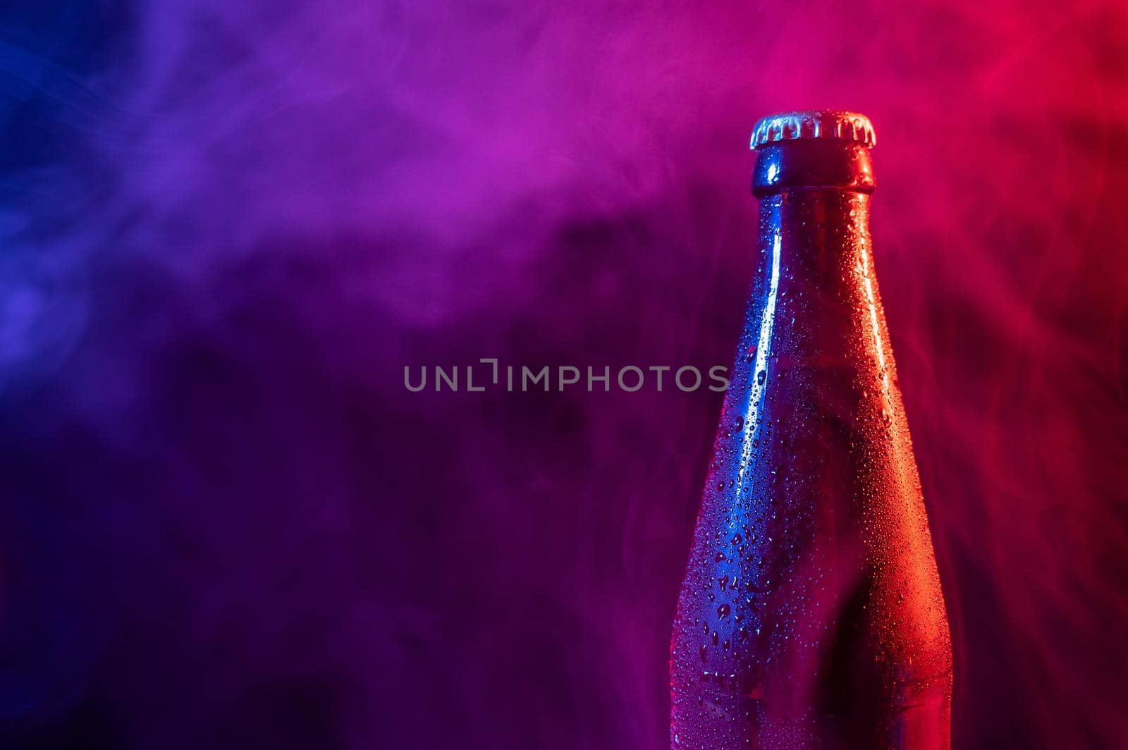 Glass bottle of beer in blue pink mist.