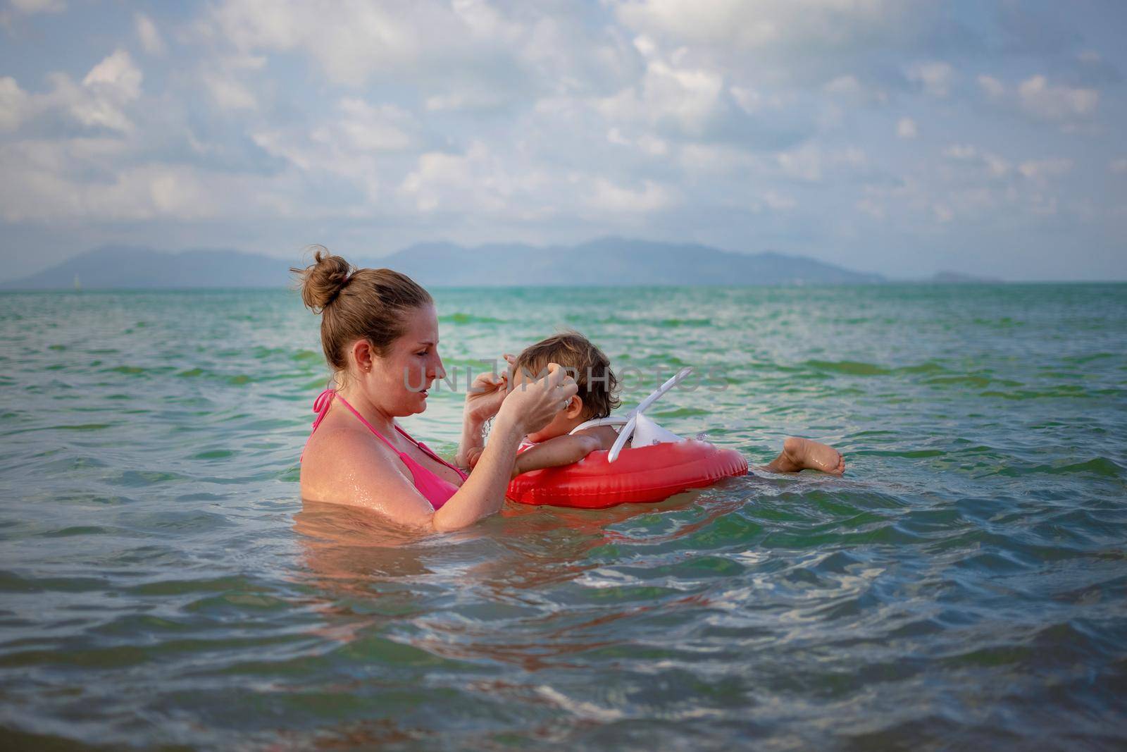 young mother and her baby Toddler swim in the sea. child in a special inflatable lifebuoy.
