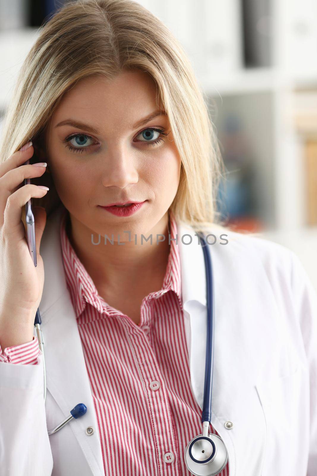 Beautiful female blond doctor talking on phone by kuprevich