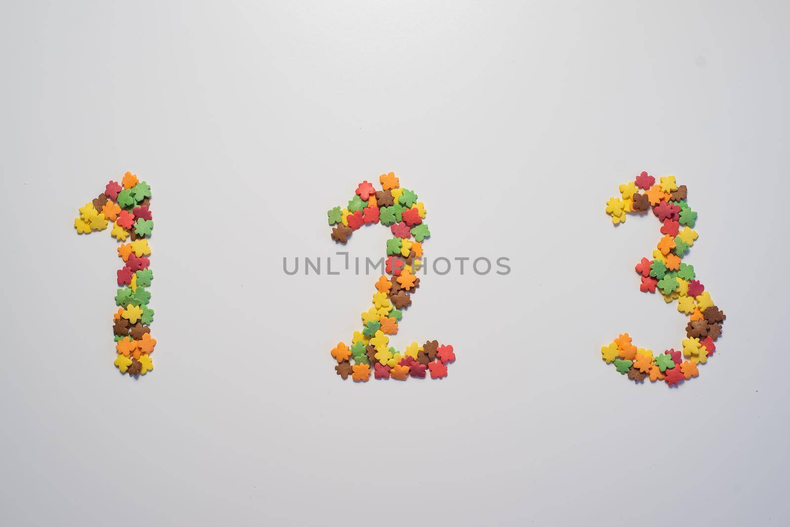 Numeral One hundred twenty three from sweet pastry topping in the form of colorful foliage on a white background