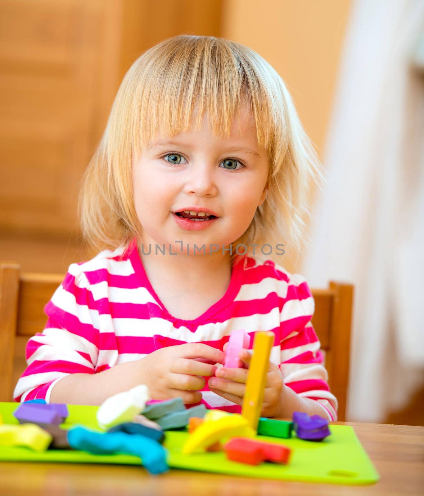 Smiling Little girl playing with plasticine at home