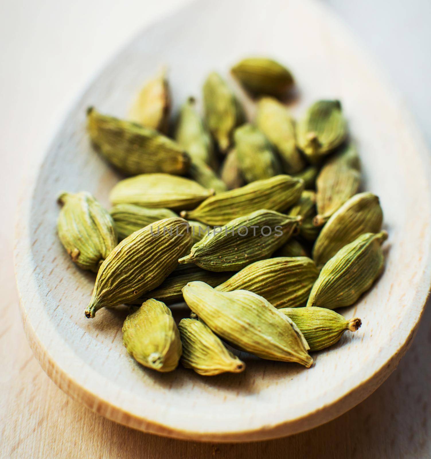 Whole cardamom in wooden spoon