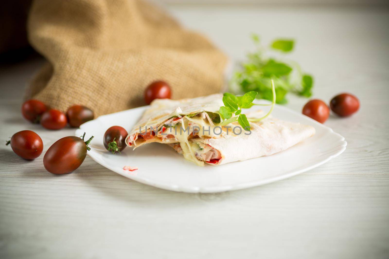 baked pita roll with filling in a plate on a wooden table