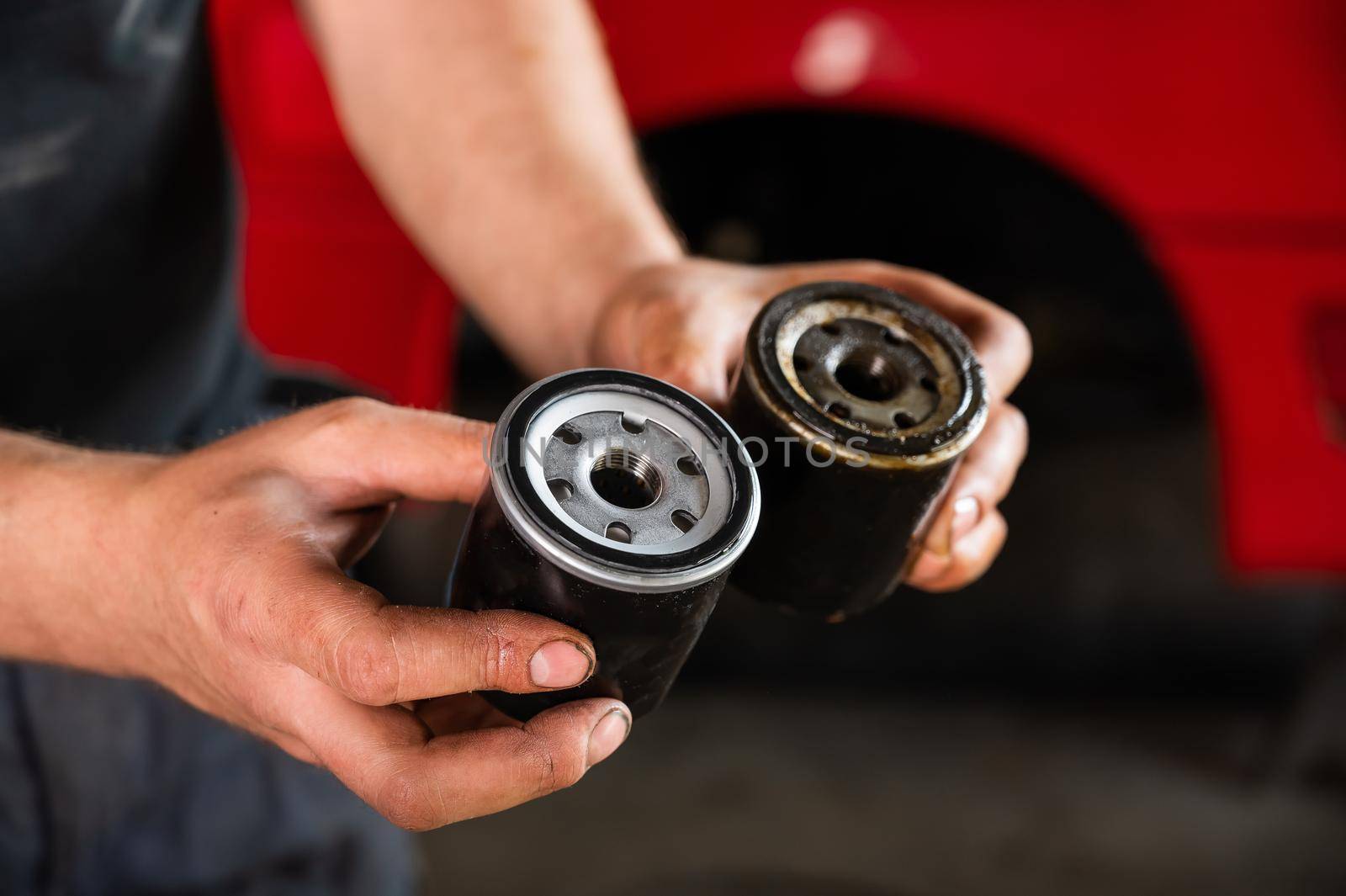 An auto mechanic holds a new and used oil filter