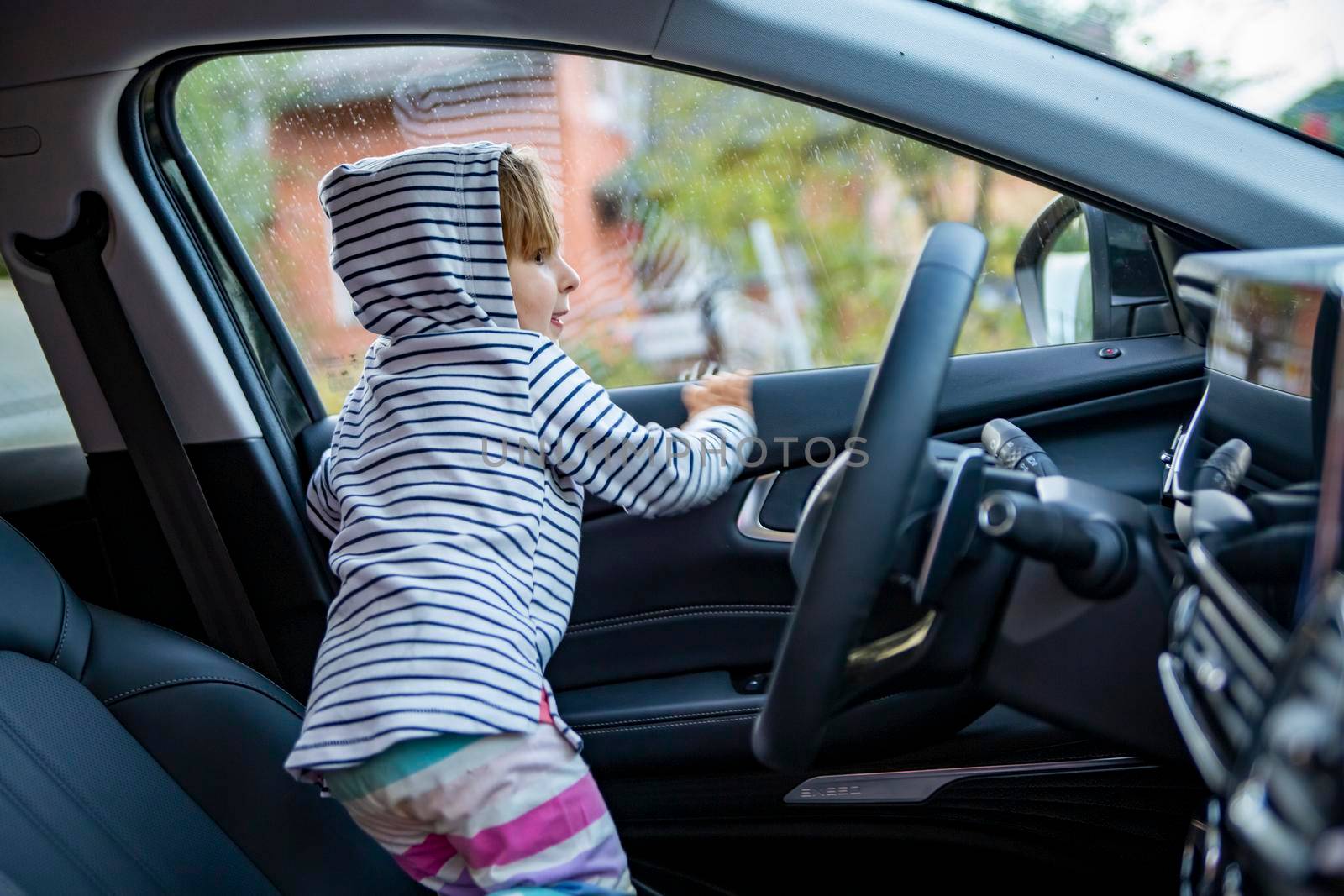 adorable toddler child plays driving on drivers seat of modern premium car. young driver concept like parent concept