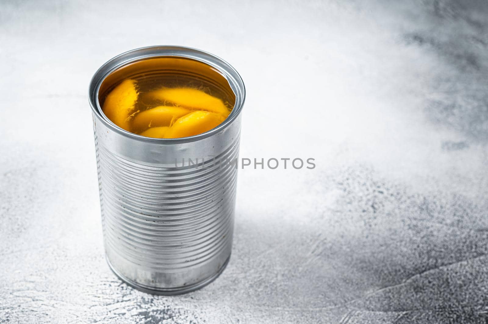 Canned mango slices in syrup in a metal can. White background. Top view. Copy space.