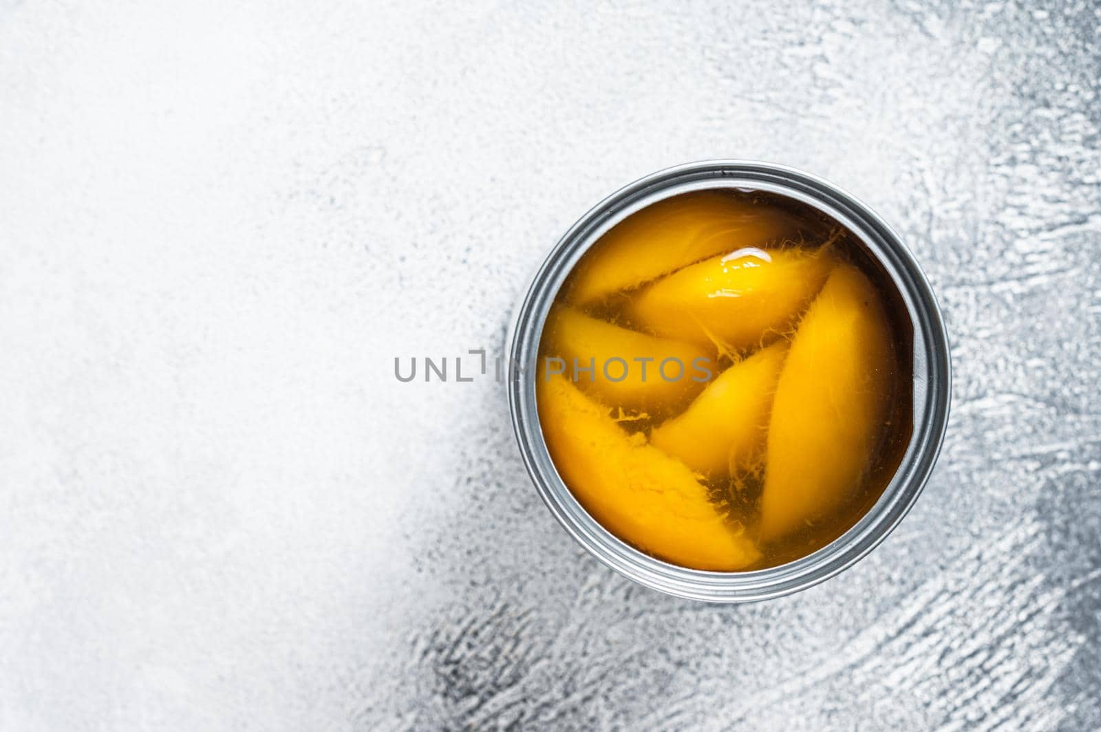 Canned mango slices in syrup in a metal can. White background. Top view. Copy space.