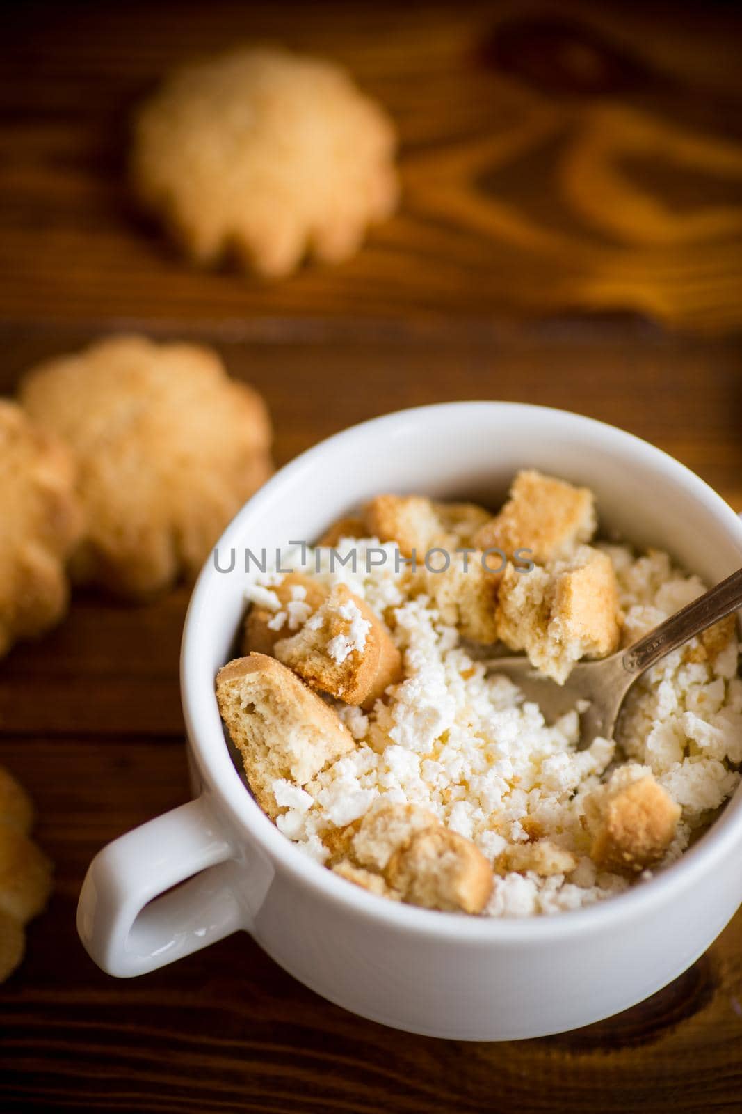 Homemade cottage cheese with pieces of shortbread cookies for breakfast, on a wooden table