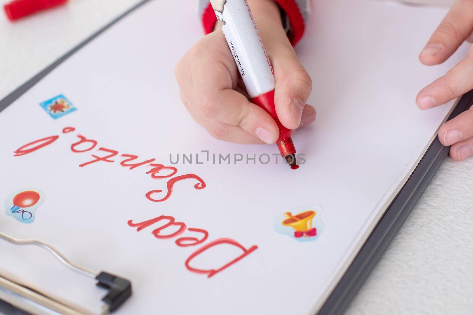 Dear Santa letter,Christmas card.girl wearing red sweater, holding a felt pen and writing on white sheet on white background.Childhood dreams about gifts.christmas and New year concept.winter holidays by YuliaYaspe1979