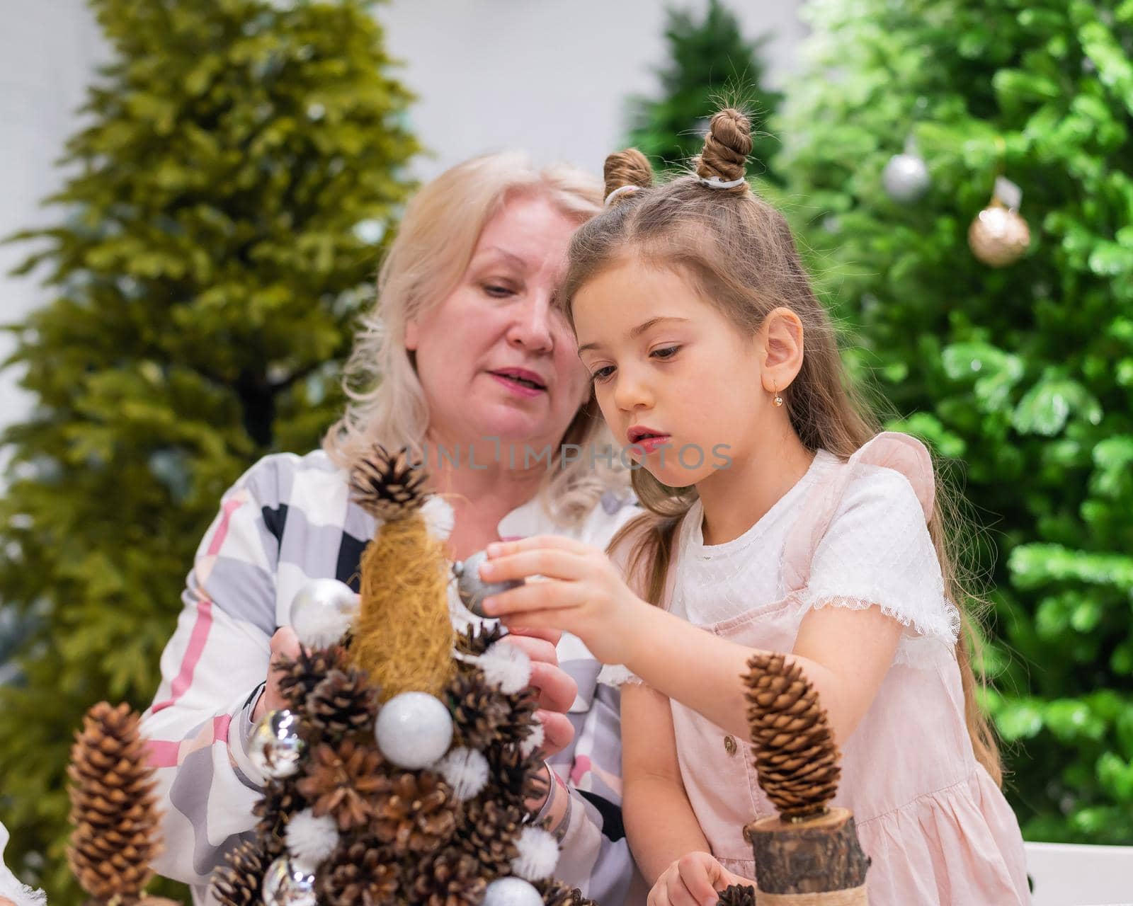 Elderly caucasian woman making pine cones decoration for christmas with two granddaughters by mrwed54
