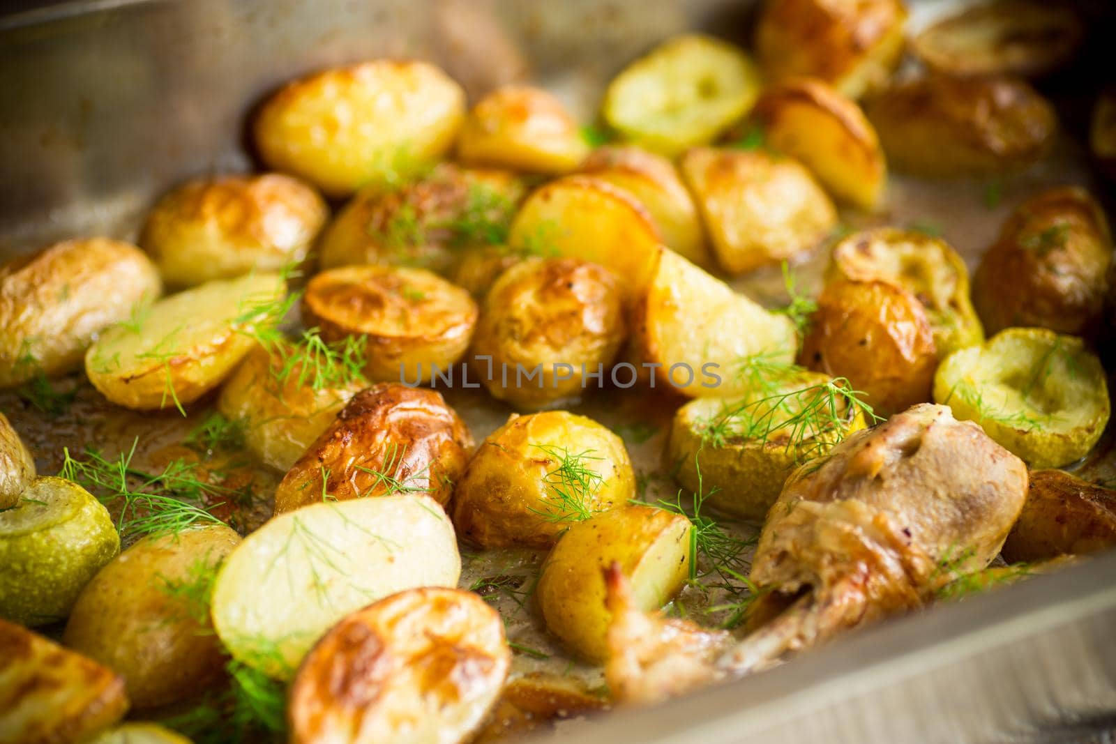 Early baked potatoes with zucchini and chicken, on a wooden table