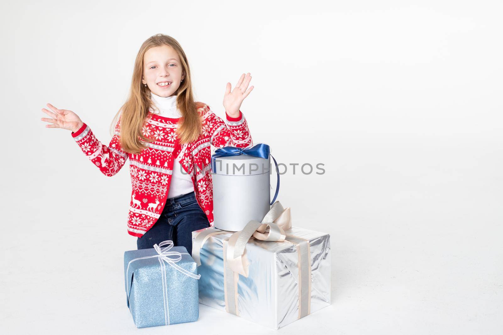 Pretty little girl wearing Christmas sweater sitting isolated on white background, holding stack of present boxes.Merry Christmas presents shopping sale.Holidays Atmosphere.new year party celebration by YuliaYaspe1979