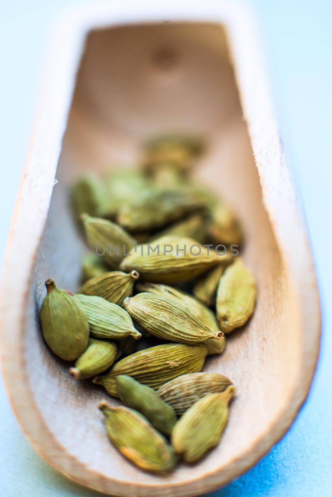 Whole cardamom in wooden spoon