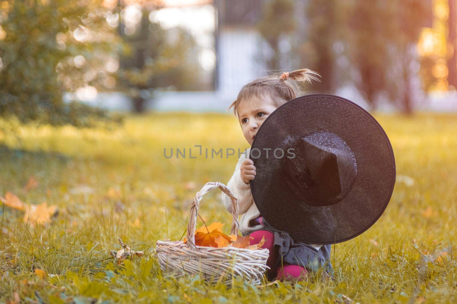 halloween concept. cute toddler hiding behind a witch hat in the autumn park by Mariaprovector