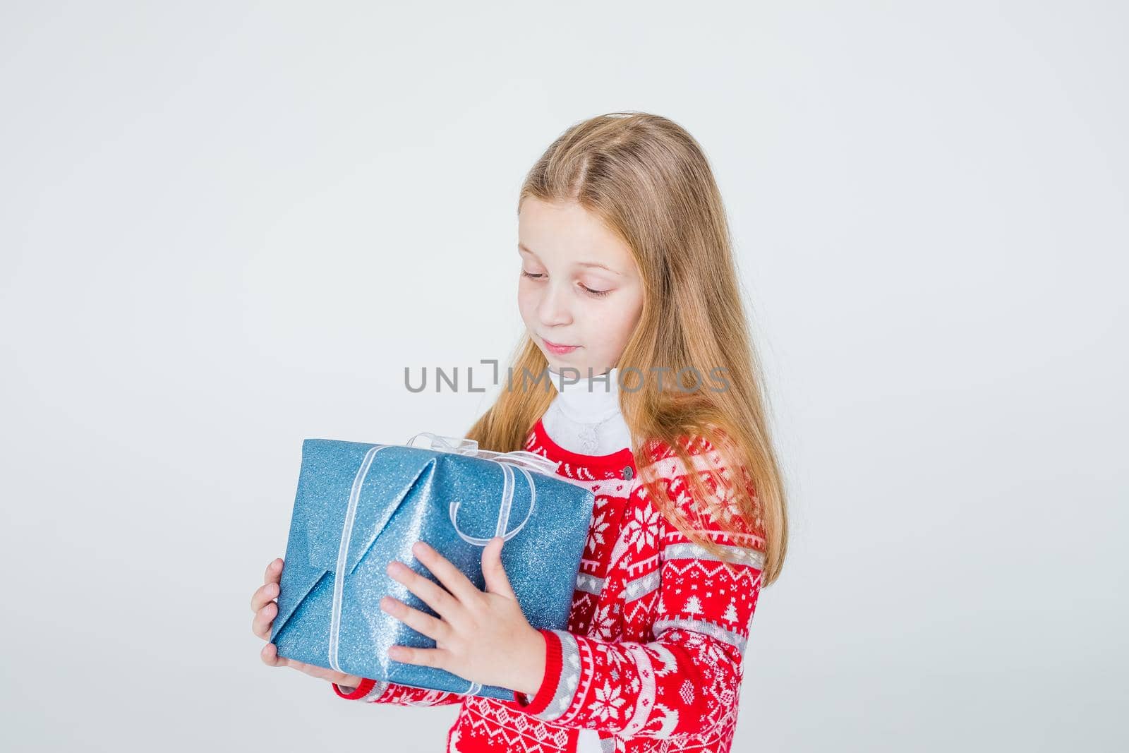 nice girl with Christmas present.Cute kid,child wears red knitted Nordic sweater holding gift, box celebrating. happy 2021 New Year. Merry Christmas presents shopping sale.holidays and people concept by YuliaYaspe1979