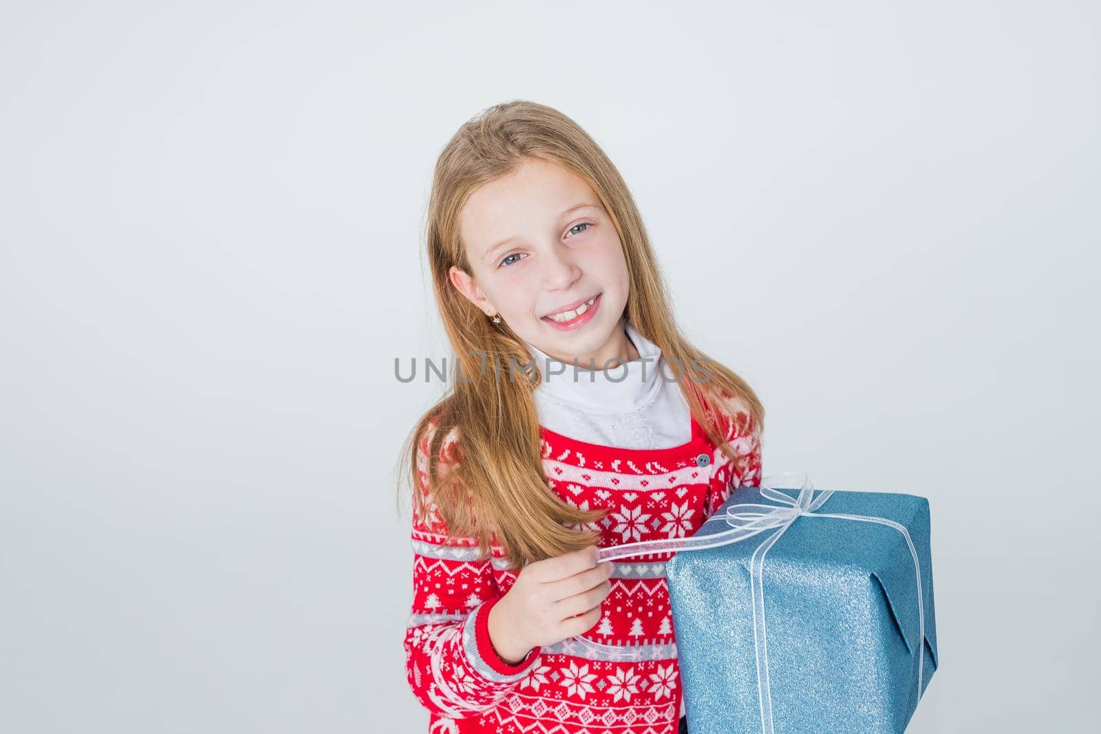 happy little girl with long hair open box with christmas present, isolated on white background.Cheerful handsome girl holding gift with bow in hands and smiling.Copy space by YuliaYaspe1979