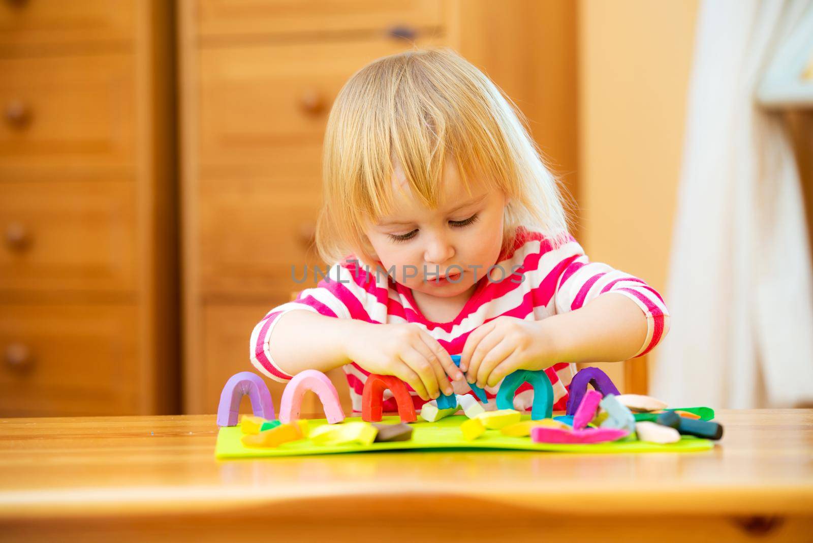 Smiling girl playing with plasticine at home