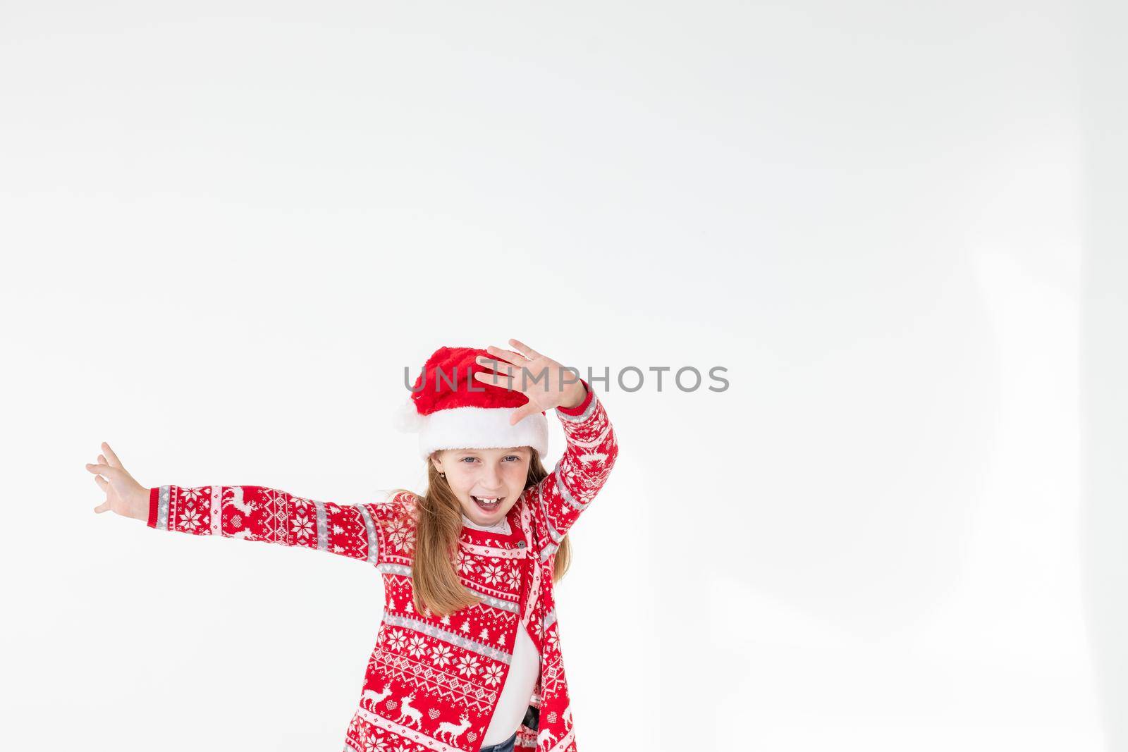 Cute funny santa's helper dancing on white background. Christmas holidays concept.New Year celebration. funny baby Santa.beautiful girl wearing red santa hat celebrating christmas day ,having fun. by YuliaYaspe1979