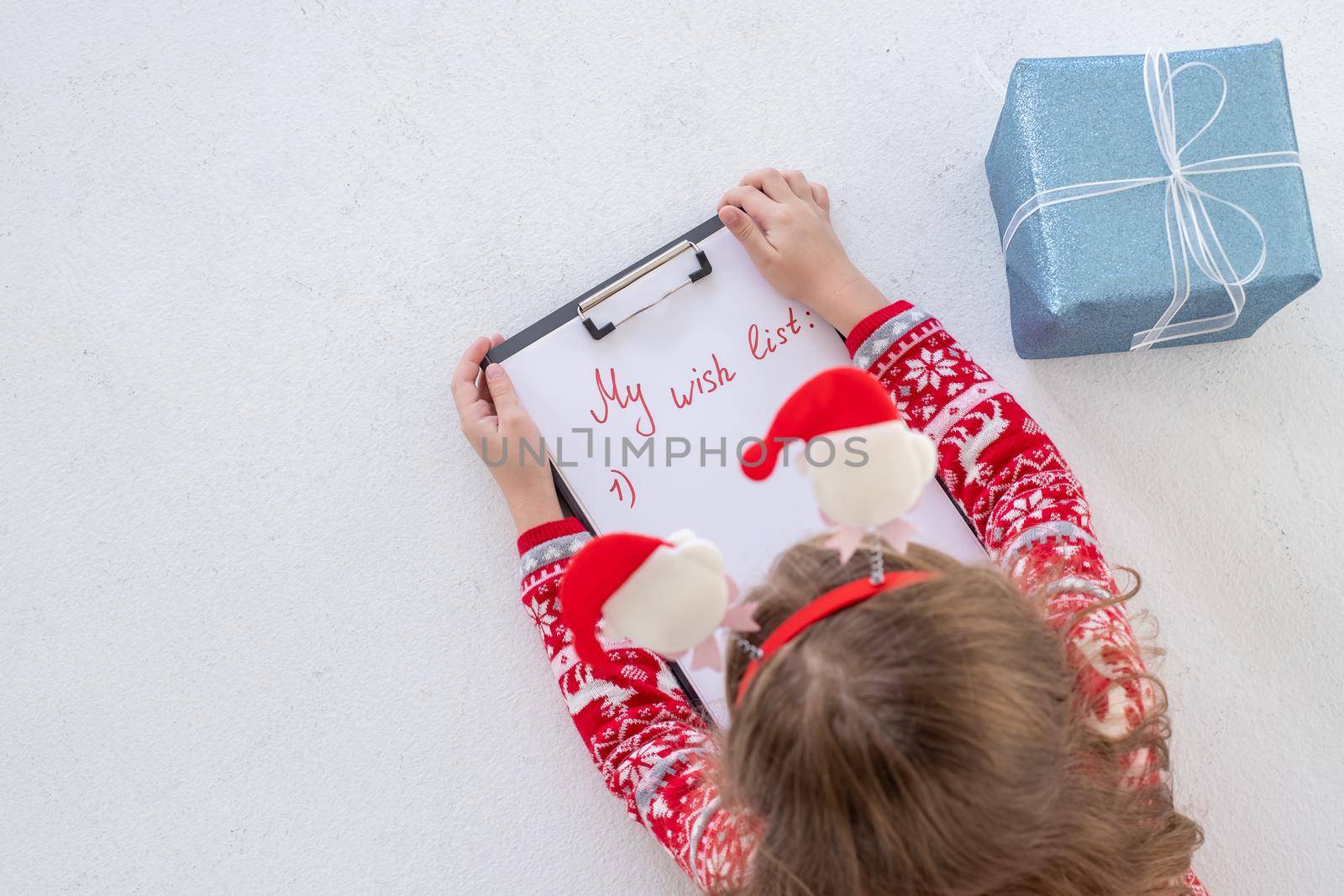 Christmas sale. Beautiful surprised child holding pen and writing.