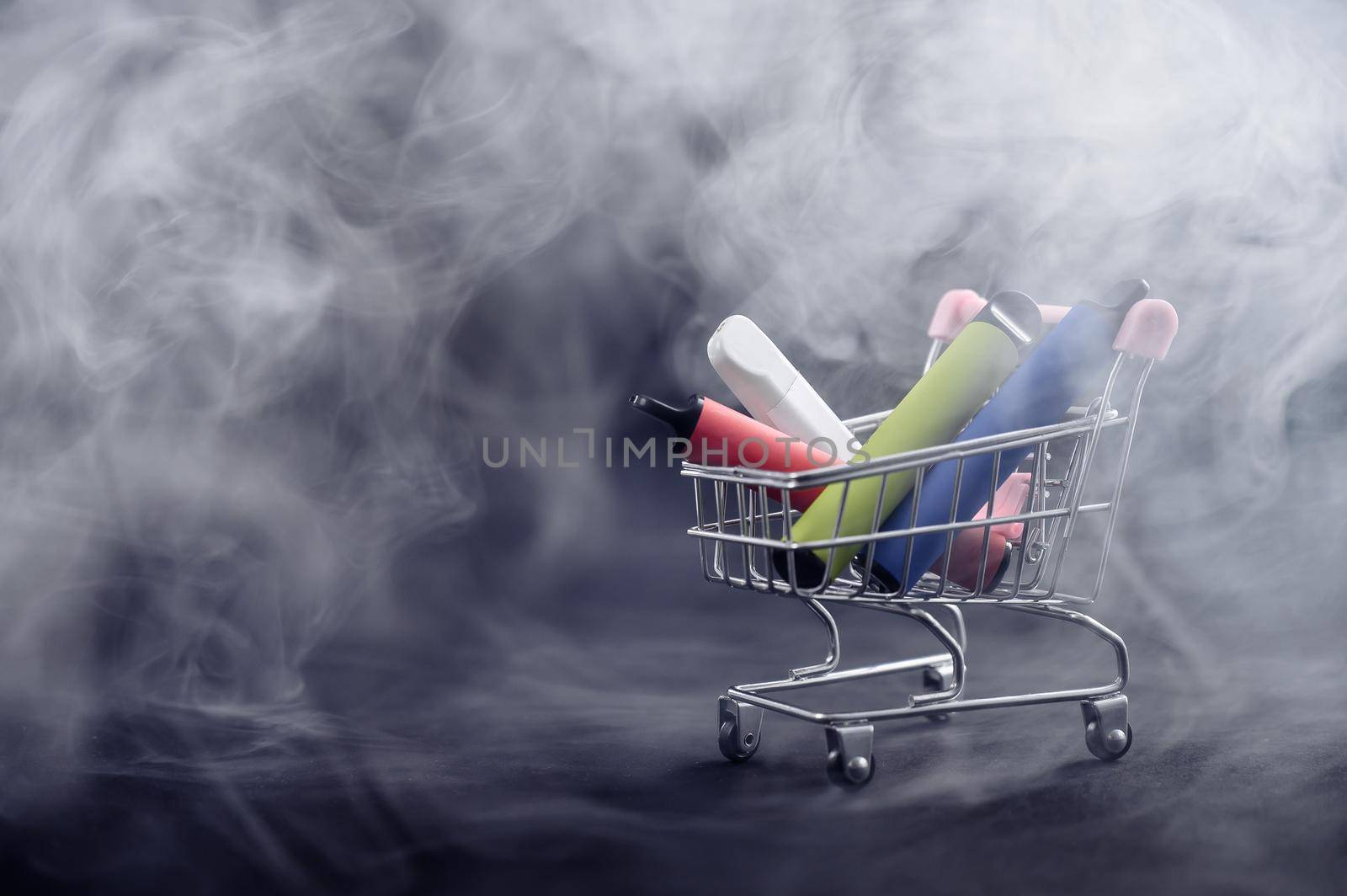 Disposable vapes in a shopping cart on a black background. Modern electronic cigarettes