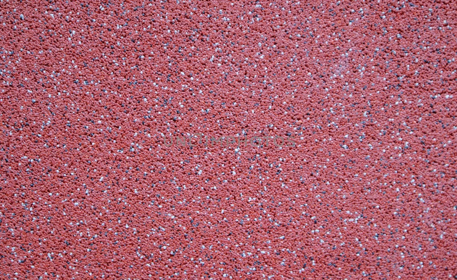 Colorful decorative mosaic plaster in burgundy or red. Wall texture, background. Granular, structured, rough, uneven textured coating. Modern exterior cladding