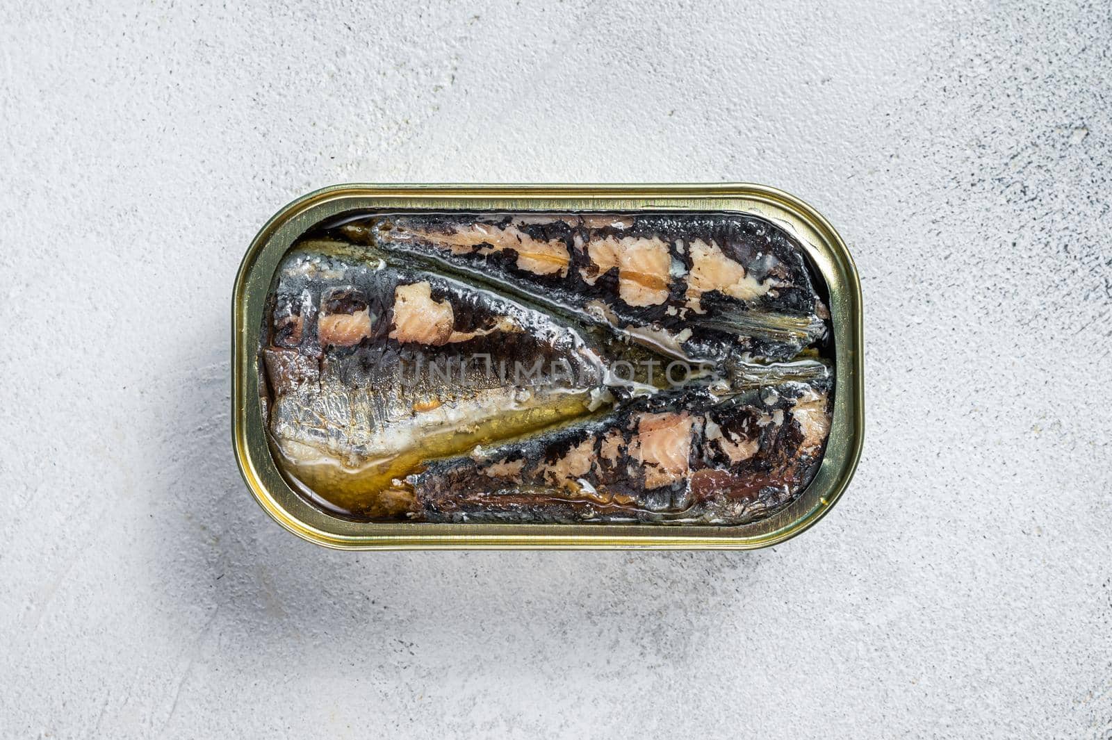 Open can with sardine in olive oil. White background. Top view.