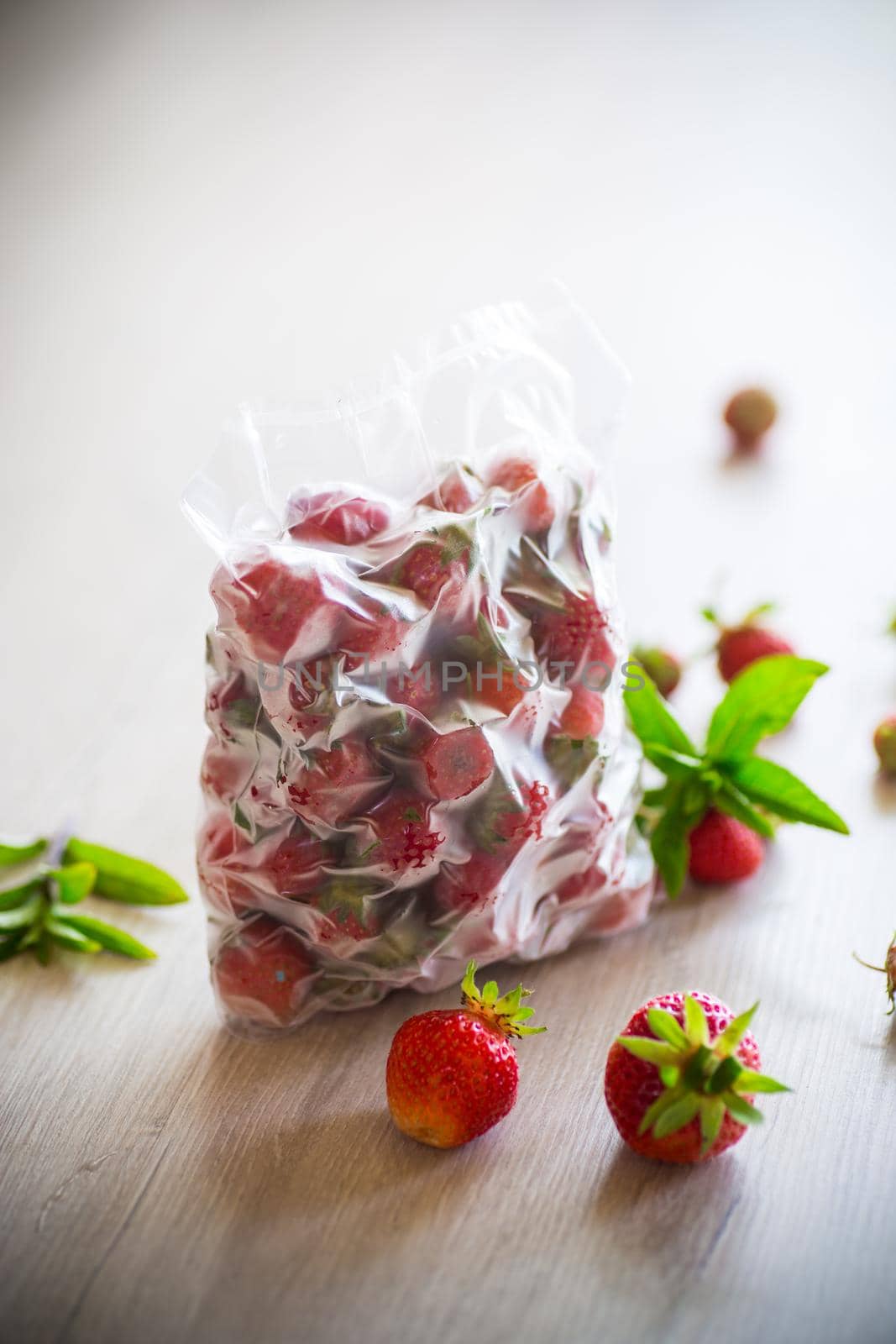 frozen fresh strawberries in a vacuum bag on a wooden table