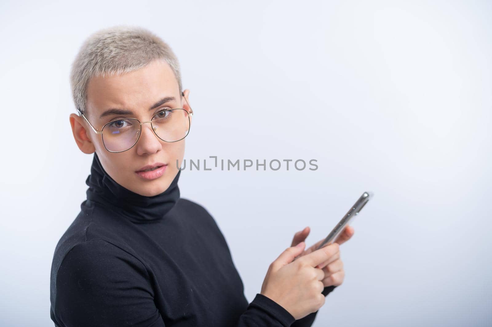 Young caucasian woman with short hair uses a smartphone on a white background. by mrwed54