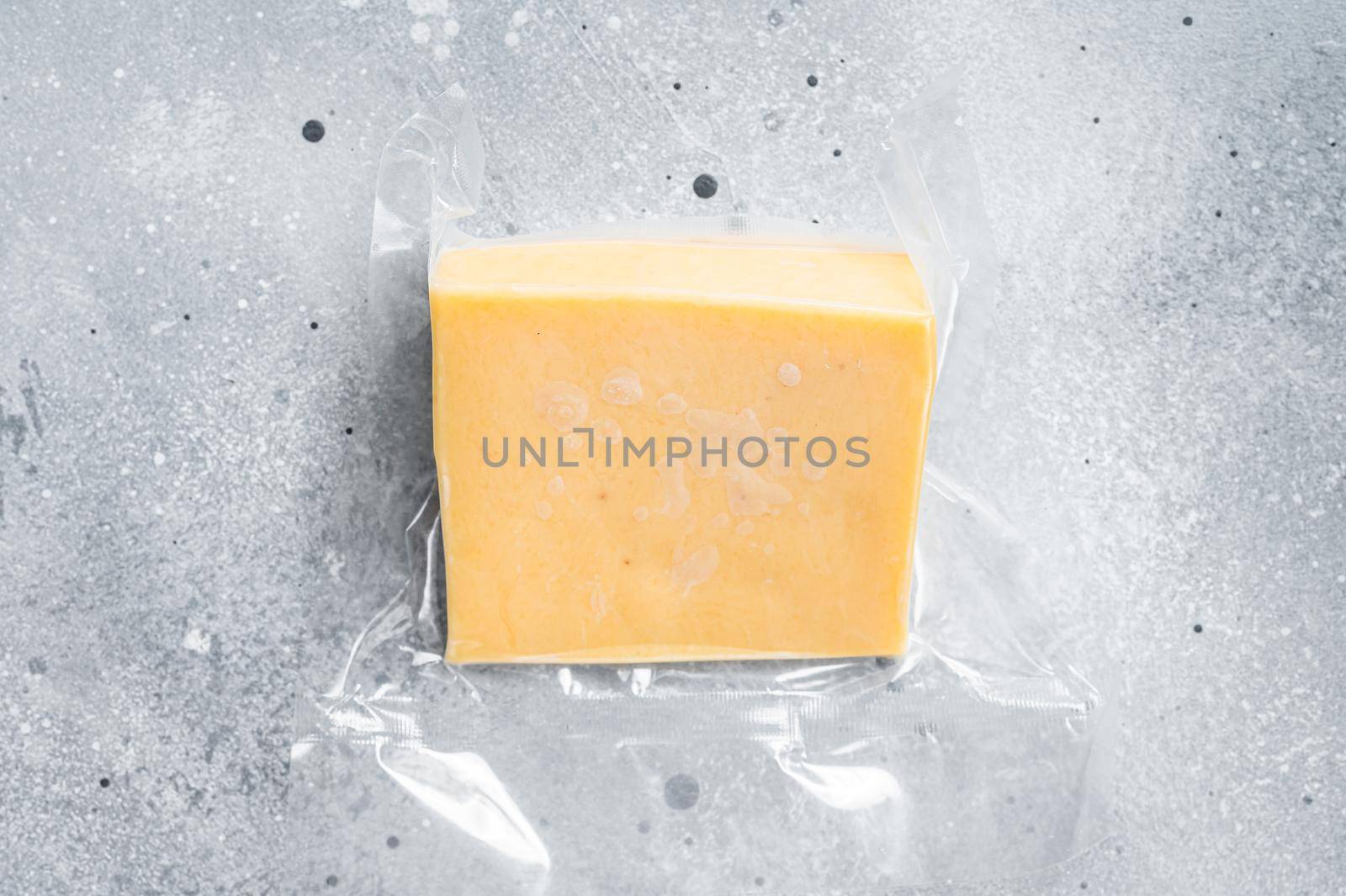 Organic Sharp Cheddar Cheese in vacuum packaging. Gray background. Top view by Composter