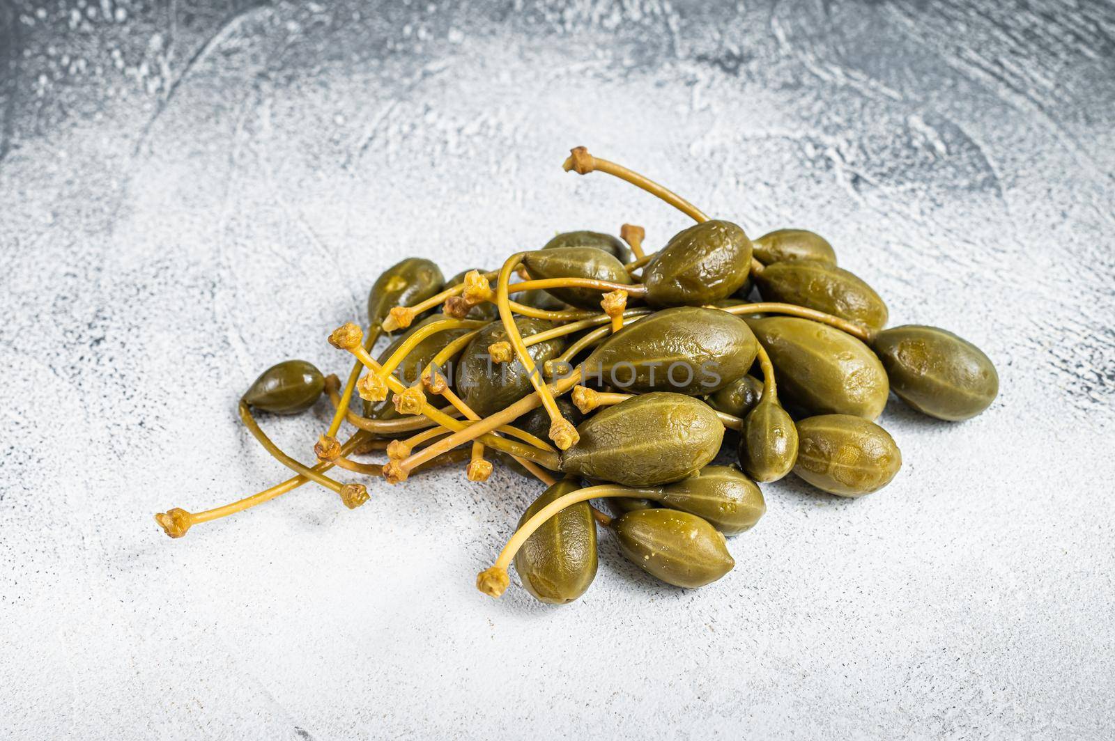 Pickled capers on a kitchen table. White background. Top view by Composter