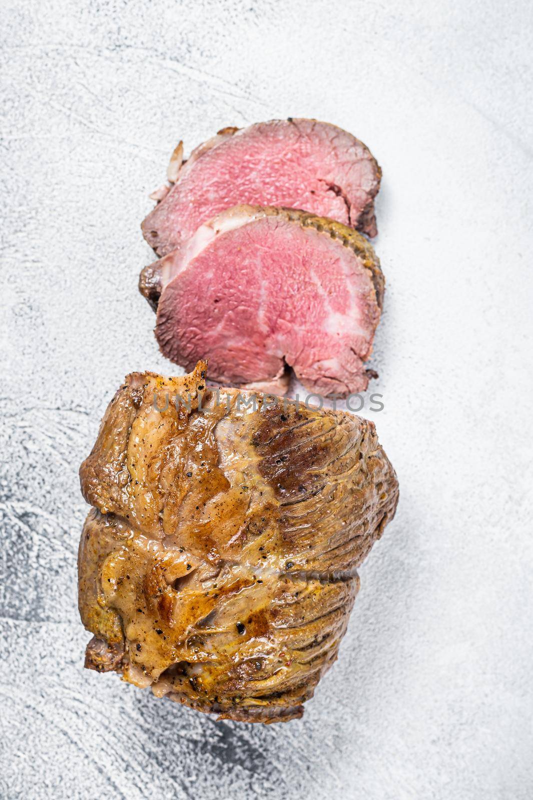 Roast beef meat fillet on kitchen table. White background. Top view.