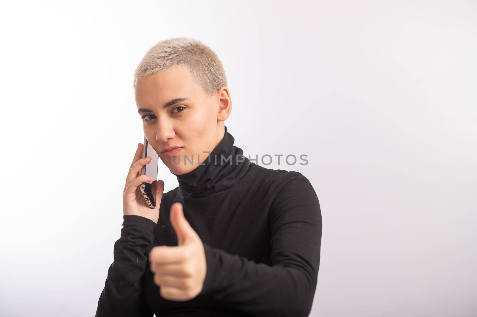 Young caucasian woman with short hair uses a smartphone on a white background. by mrwed54