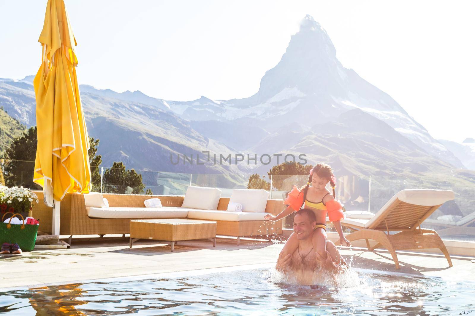 Family In Swimming Pool In Mountains. Beautiful outdoor scene in Swiss Alps, Switzerland, Europe.