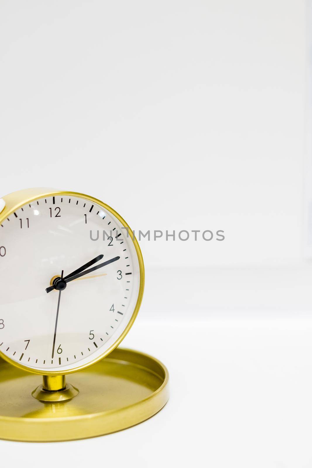 Old alarm clock with ten minutes past two. Date and time reminder or deadline concept, small clock on white background, counting down to holiday, vacation or end of month.Time Management. Copy space by YuliaYaspe1979