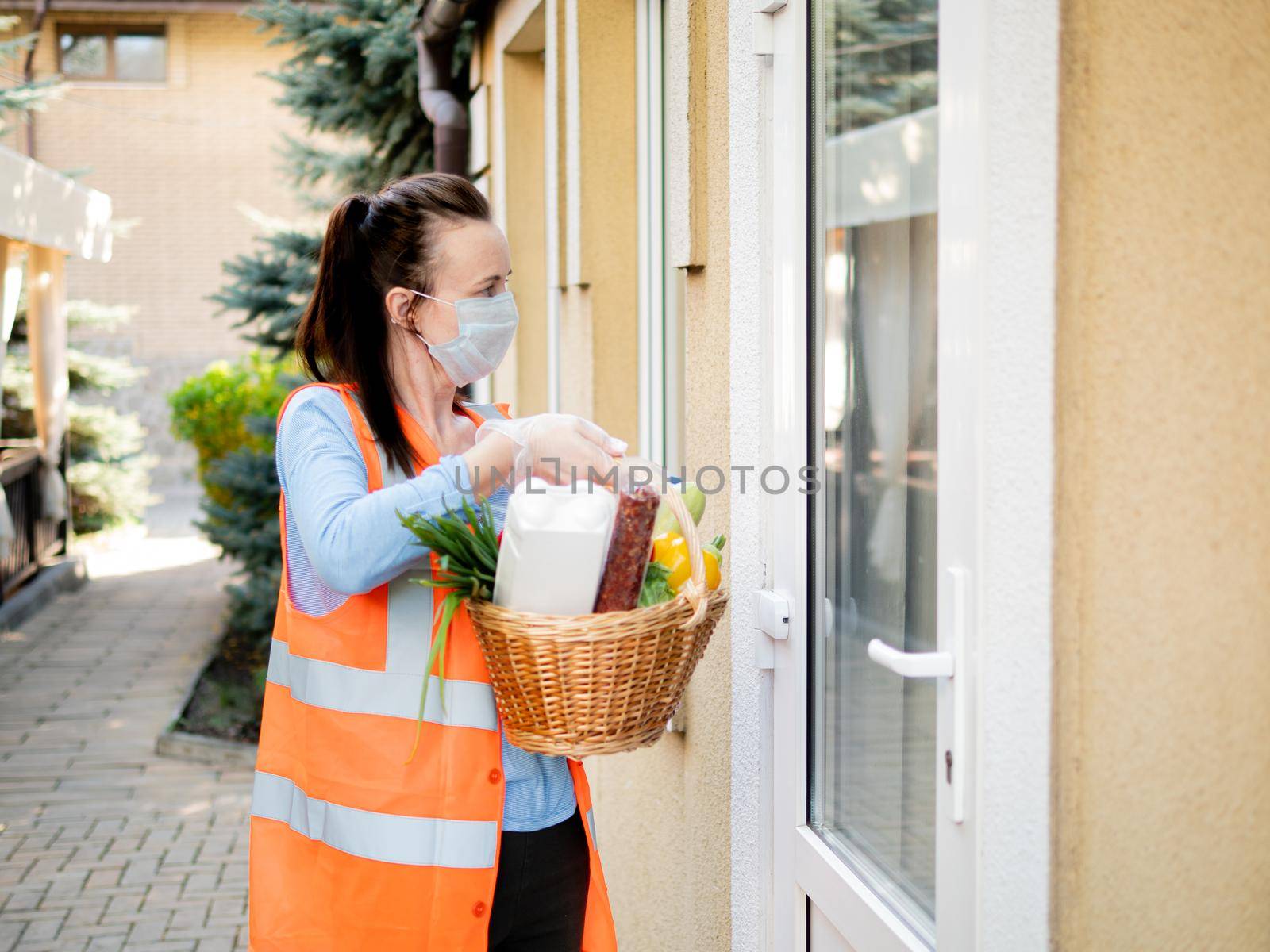 Food delivery by a volunteer during quarantine. A volunteer girl knocks on the door of a person who is on self-isolation. by Utlanov