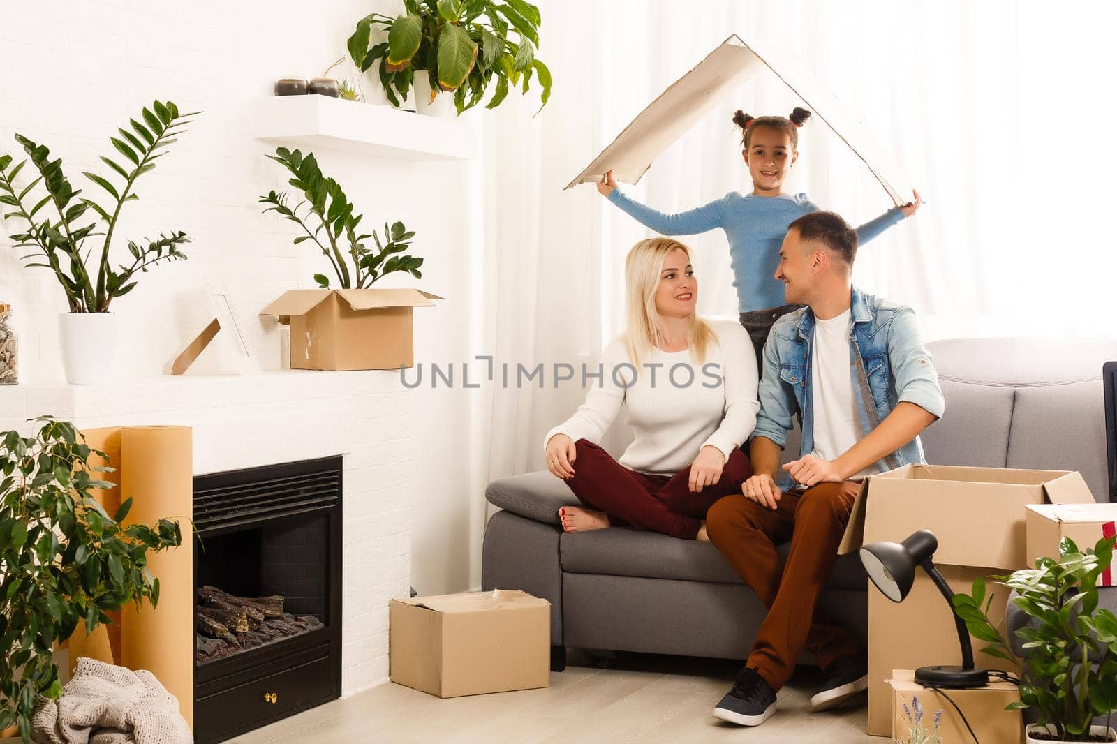 Happy family sitting on wooden floor. Father, mother and child having fun together. Moving house day, new home and design interior concept