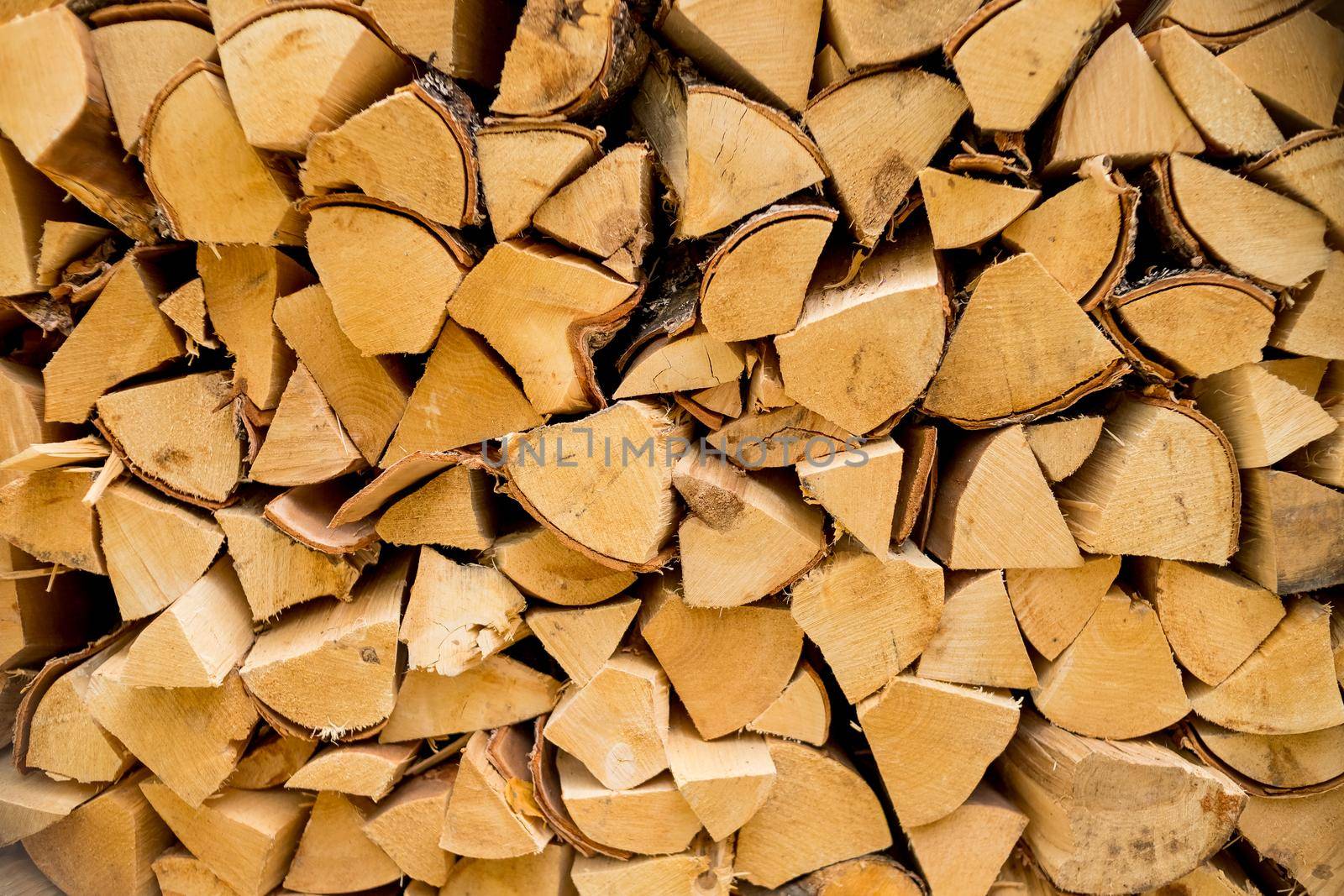 Pile of stacked triangle firewood prepared for fireplace and boiler.dry chopped firewood logs ready for winter.Birch background. by YuliaYaspe1979