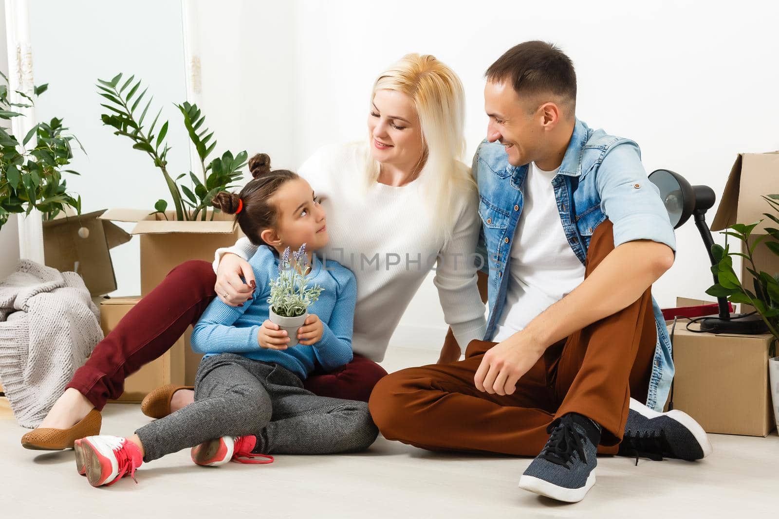 Happy family sitting on wooden floor. Father, mother and child having fun together. Moving house day, new home and design interior concept by Andelov13