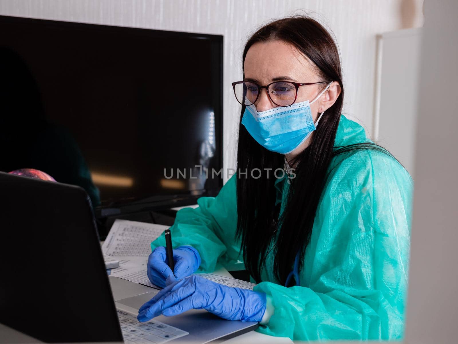 Female doctor in medical mask works with the computer. by Utlanov