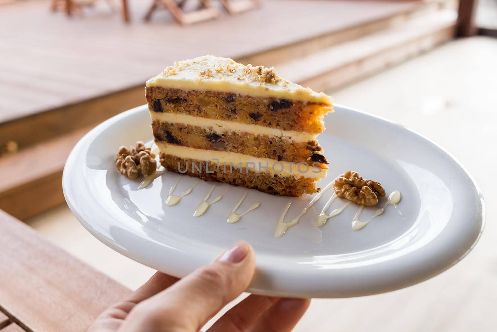 carrots and pumpkin cake with coffee cream in a cut on the plate.Delicious sliced carrot cake.Slice of cake on a white ceramic plate in hand, decorated with walnuts, by YuliaYaspe1979